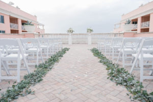 Romantic Boho Chic Inspired Wedding Ceremony Decor, White Folding Chairs, Silver Dollar Eucalyptus Greenery Aisle Decor, White Pedestals with White and Greenery Floral Bouquets | Planner Parties A'la Carte | Florist Bruce Wayne Florals | Waterfront Tampa Bay Hotel Venue Hyatt Regency Clearwater Beach