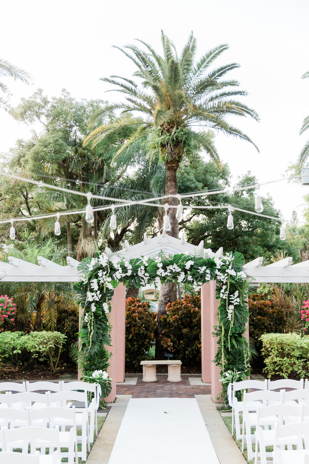 Romantic, Modern, Tropical Wedding Decor, Ceremony Arch with Monstera Leaves, Green Palm Fronds, White Orchids, Hanging Lights | The Tea Garden at The Vinoy Renaissance St. Petersburg Resort & Golf Club | Tampa Bay Florist Bruce Wayne Florals Florida Luxury Wedding Planner Parties A'La Carte