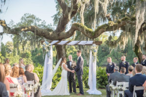Florida Bride and Groom Exchanging Vows Under Wooden Arch with White Draping and Blue and White Flower Bouquets on Golf Course Wedding Ceremony Portrait | Tampa Bay Wedding Photographer Kristen Marie Photography | Innisbrook Golf & Spa Resort Wedding Venue
