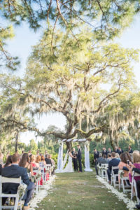 Florida Bride and Groom Exchanging Vows Under Wooden Arch with White Draping and Blue and White Flower Bouquets on Golf Course Wedding Ceremony Portrait | Tampa Bay Wedding Photographer Kristen Marie Photography | Innisbrook Golf & Spa Resort Wedding Venue