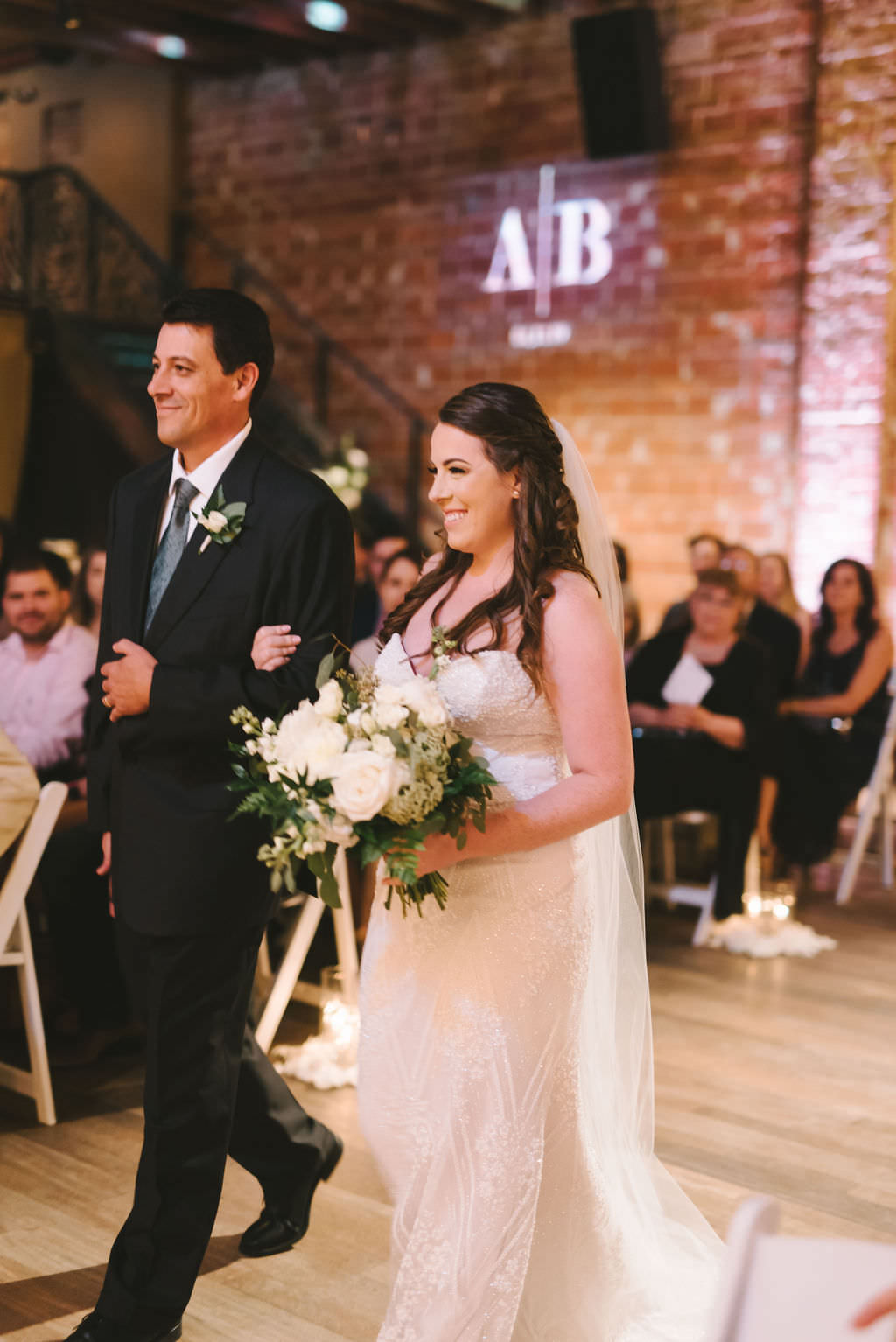 Modern Florida Bride and Father Walk Down the Aisle, Holding White and Greenery Floral Bouquet, Indoor Wedding Processional | Tampa Bay Venue NOVA 535 | St. Pete Photographer Kera Photography