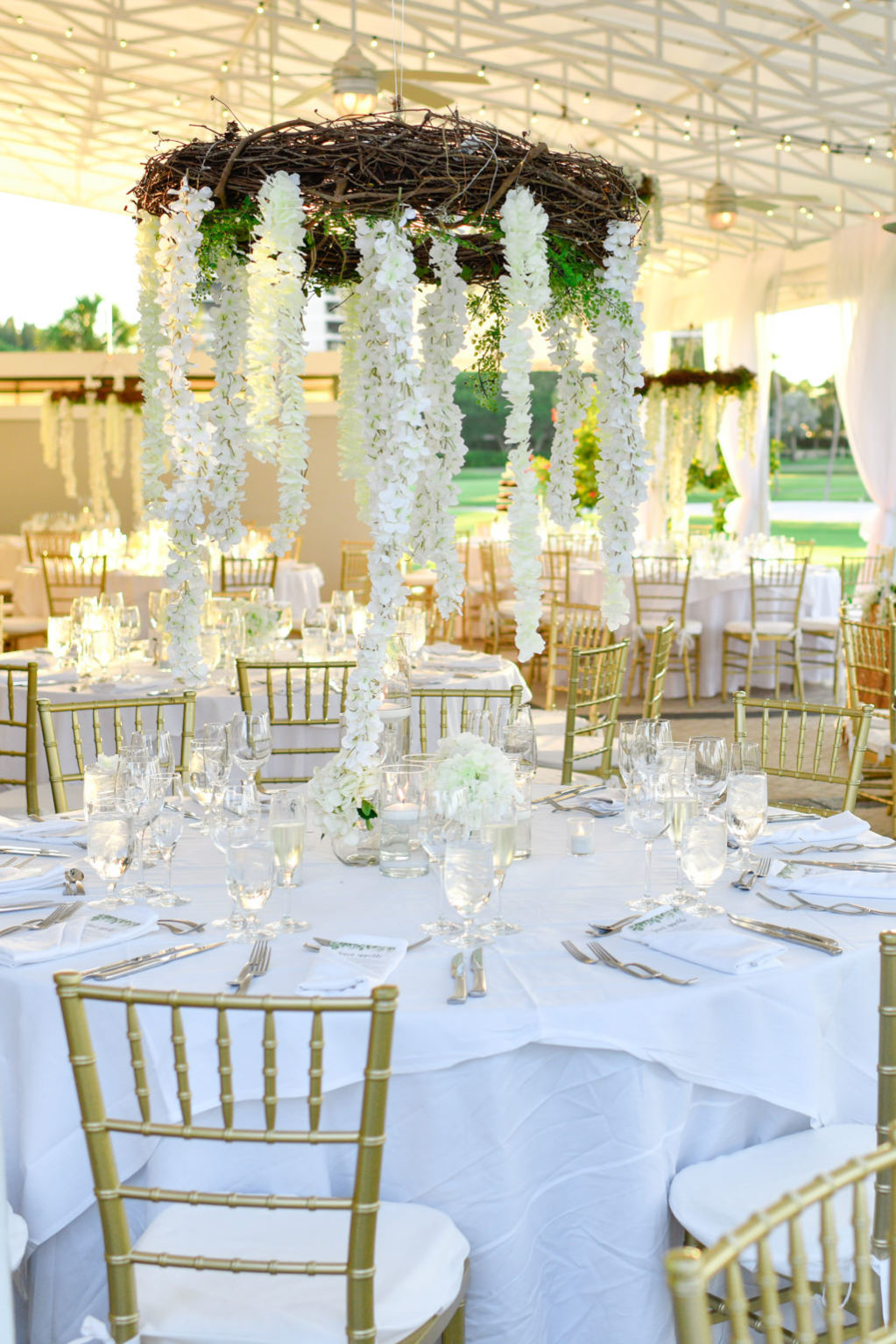 Tropical Classic Elegant Wedding Reception Decor, Round Tables with White Tablecloths, Gold Chiavari Chairs, Low White Floral Centerpieces, Hanging Wooden Branch Wreath with White Wisteria Flowers | Sarasota Wedding Venue The Resort at Longboat Key Club