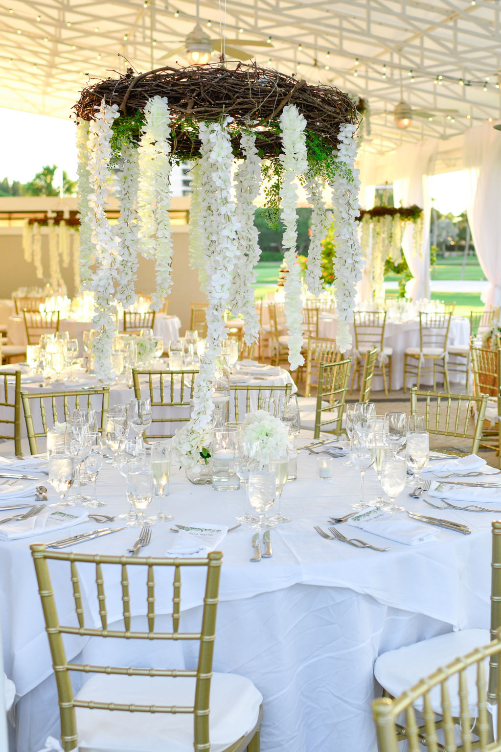 Tropical Classic Elegant Wedding Reception Decor, Round Tables with White Tablecloths, Gold Chiavari Chairs, Low White Floral Centerpieces, Hanging Wooden Branch Wreath with White Wisteria Flowers | Sarasota Wedding Venue The Resort at Longboat Key Club