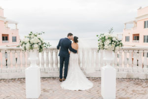Florida Bride and Groom Intimate Wedding Portrait on Rooftop Terrace, White Pedestals with White, Ivory and Greenery Floral Bouquets | Waterfront Hotel Wedding Venue Hyatt Regency Clearwater Beach | Tampa Bay Rooftop Wedding Ceremony | Florist Bruce Wayne Florals | Planner Parties A'la Carte