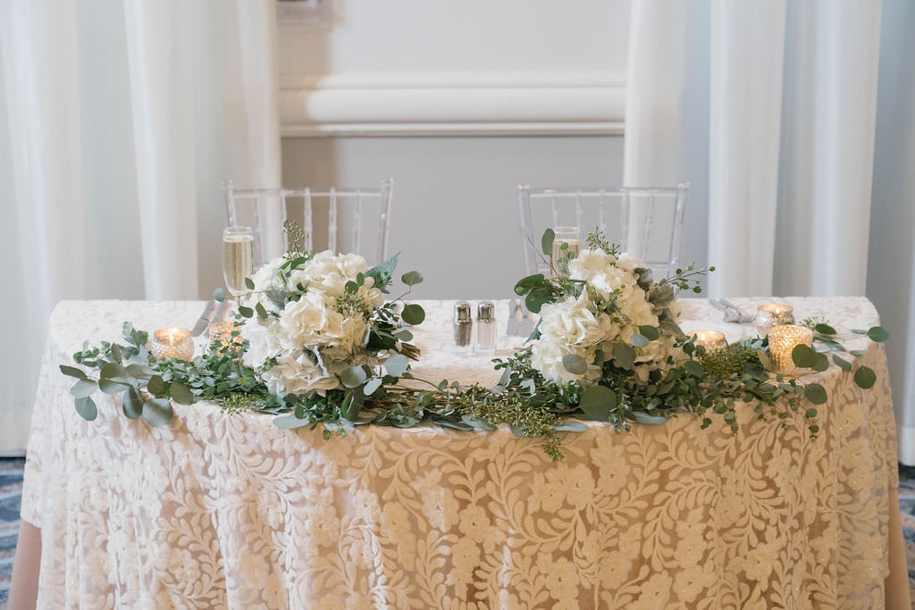 Romantic Boho Chic Wedding Reception Decor, Sweetheart Table with Floral Ivory Tablecloth, Greenery Garland, White Ivory Floral Bouquets, Clear Acrylic Chiavari Chairs | Planner Parties A'la Carte | Florist Bruce Wayne Florals | Rentals A Chair Affair, Over the Top Rental Linens