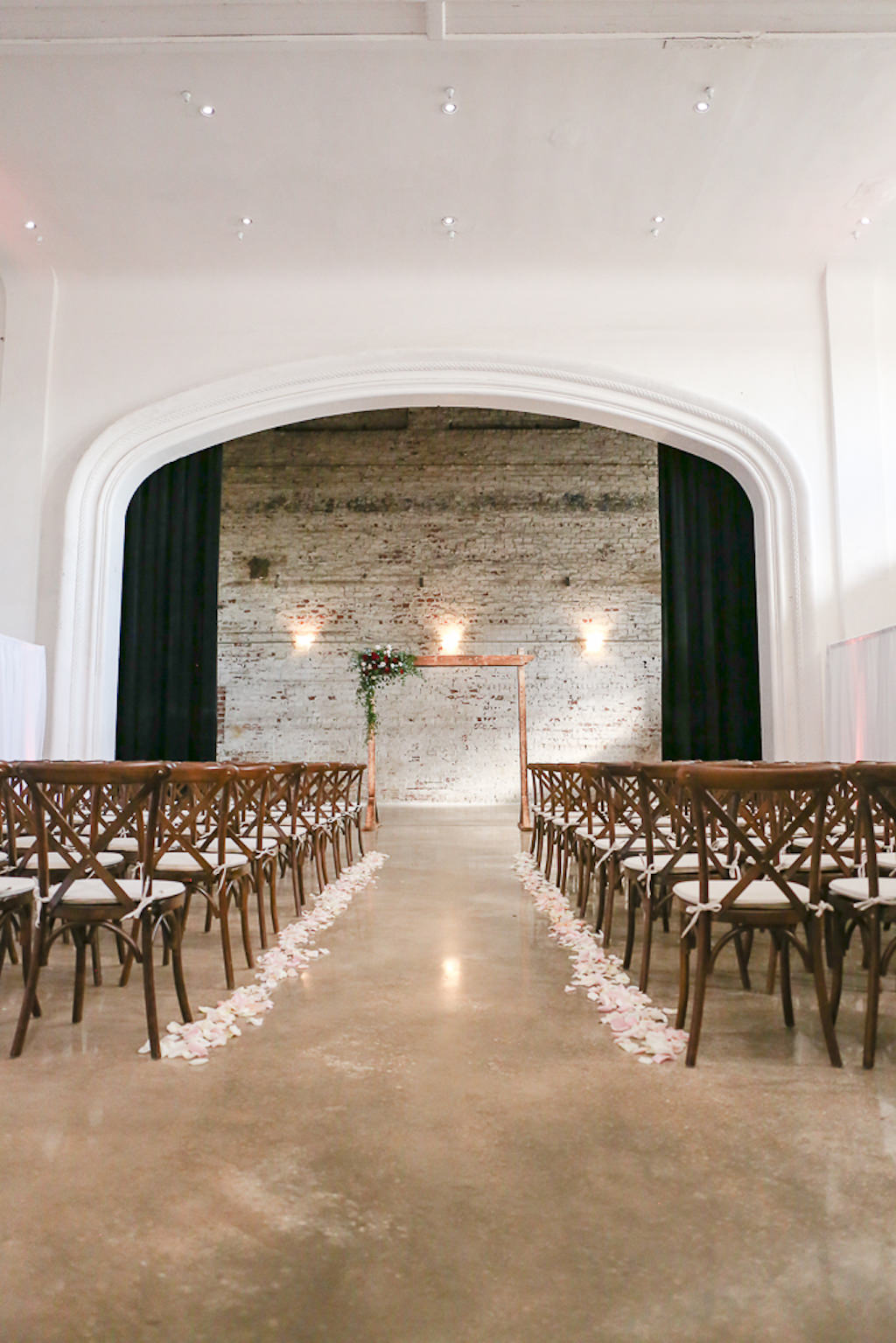 Industrial Elegant Wedding Ceremony Decor, White Brick Wall Backdrop, Wooden Chiavari Chairs, Blush Floral Petal Aisle, Wooden Arch with Greenery Accent | Tampa Wedding Photographer Lifelong Photography Studios | Tampa Wedding Planner Breezin' Weddings | Tampa Bay Wedding Venue Rialto Theatre