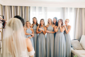 Bridesmaids in Matching Cross Halter Long Dusty Blue Dresses First Reaction Wedding Portrait to Seeing Bride