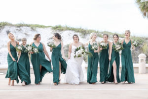 Clearwater Beach Florida Bride and Bridesmaids in Matching Green Dresses Holding Greenery and White Floral Bouquets, Bride in Spaghetti Strap Fitted Lace V Neckline Wedding Dress with Rhinestone Belt | Tampa Bay Wedding Photographer Lifelong Photography Studios