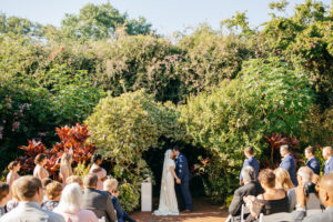 Florida Bride and Groom Exchanging First Kiss Garden Wedding Ceremony Portrait | Outdoor Tropical Inspired St. Pete Wedding Venue | Sunken Gardens