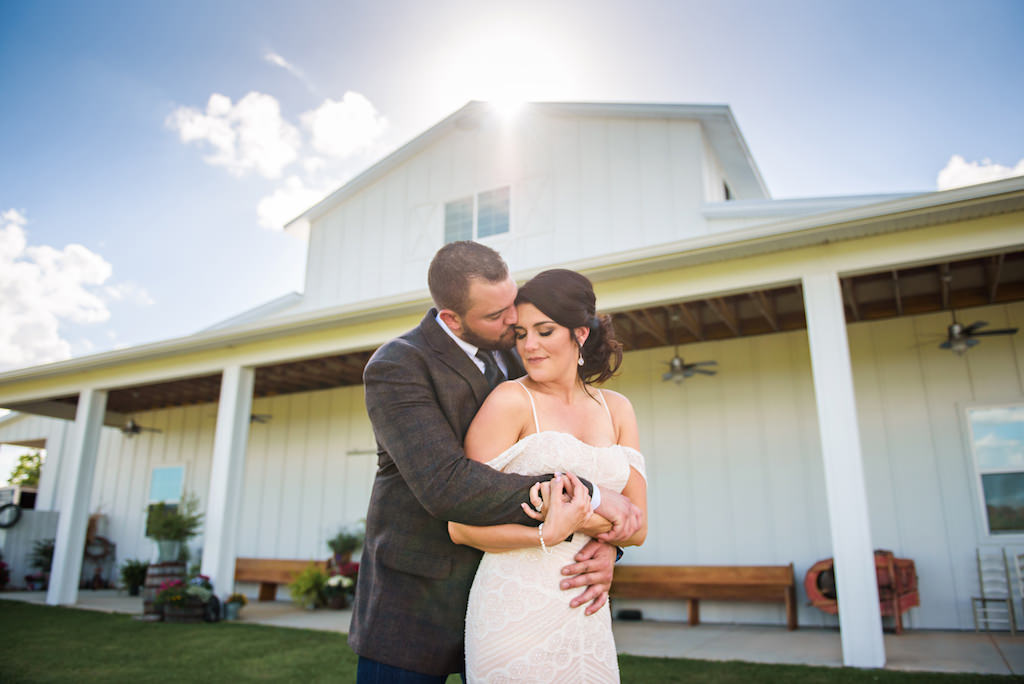 Florida Bride and Groom Kissing Wedding Portrait Outside White Farmhouse Barn | Tampa Bay Rustic Wedding Venue Covington Farms