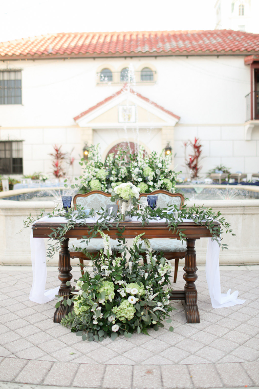 Rustic Elegant Wedding Reception Decor, Wooden Sweetheart Table with White Table Runner, Greenery, White, Ivory Floral Arrangements and Centerpiece | Wedding Photographer Lifelong Photography Studios | Wedding Venue Bishop Museum of Science and Nature | Sarasota Wedding Planner Kelly Kennedy Weddings and Events