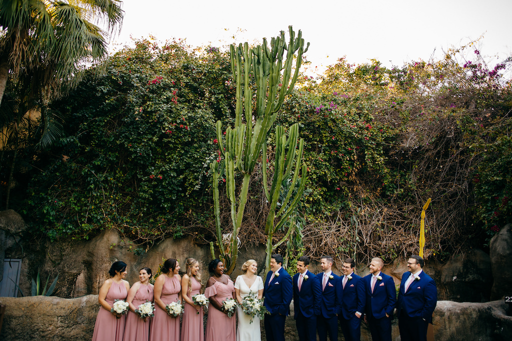 Florida Bride, Groom, Bridesmaids in Mauve Pink Dresses Holding White Floral Bouquets, Groomsmen in Blue Suits with Pink Ties Wedding Party Garden Portrait with Tall Cactus | Tampa Bay Outdoor Wedding Venue Sunken Gardens