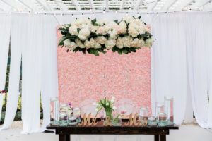Modern, Whimsical Garden Wedding Decor and Sweetheart Table, Pink Floral Boxwood Wall, White Draping, Ivory, Blush Pink Hanging Floral Arrangement with Greenery, Clear Floating Candles, Gold Mr. and Mrs. Tabletop, White Lilly Bouquet, Sweetheart Table with Ghost Acrylic Chairs, Outdoor Dance Floor | Tampa Bay Wedding Planner Special Moments Event Planning | Tampa Bay Wedding Florist Gabro Event Services | Tampa Bay Wedding Rentals A Chair Affair