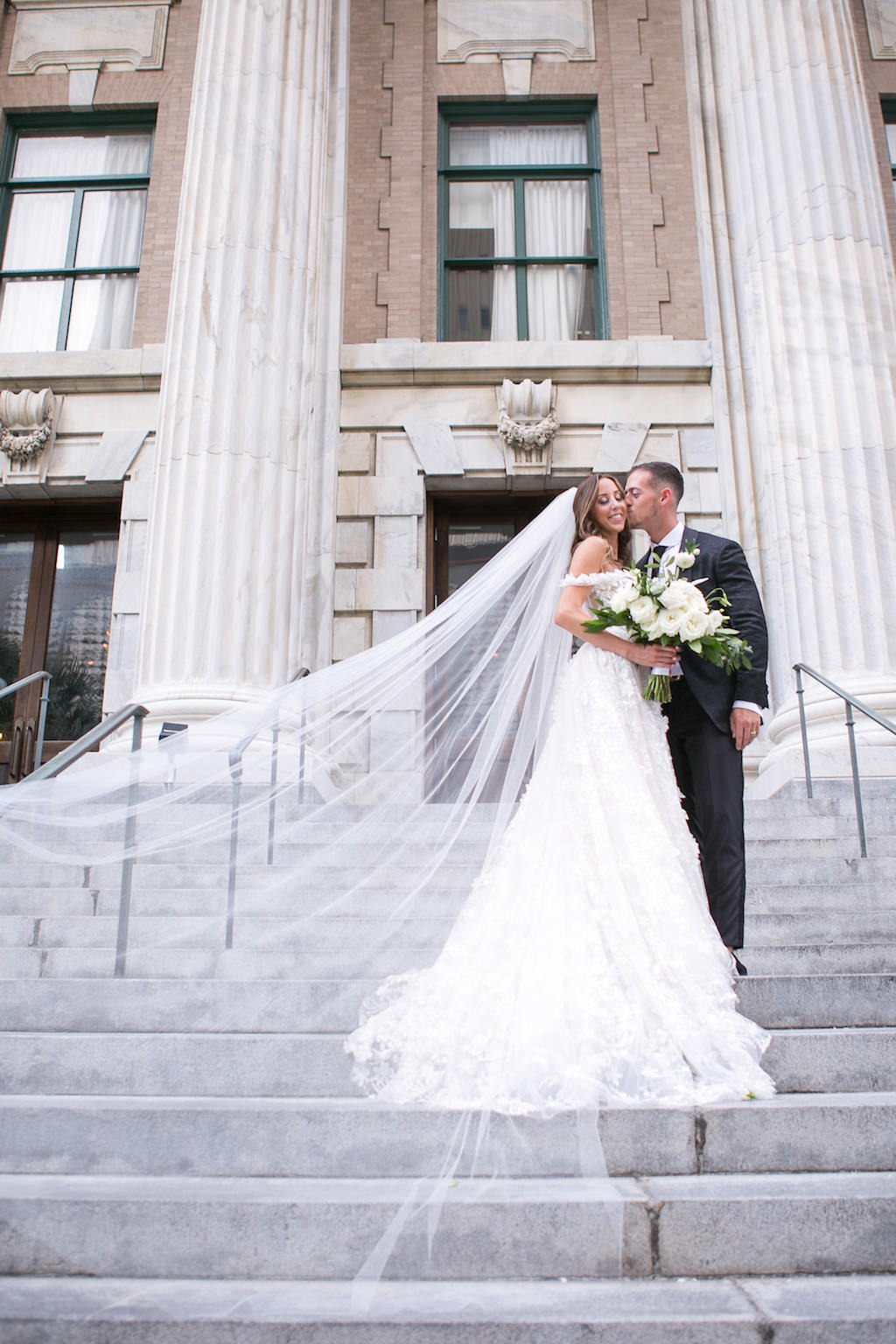 Elegant Florida Bride and Groom Wedding Portrait on Steps of Downtown Tampa Hotel Venue Le Meridien and Veil Blowing in Wind | Tampa Bay Wedding Photographer Carrie Wildes Photography | Tampa Dress Shop Isabel O'Neil Bridal Collection
