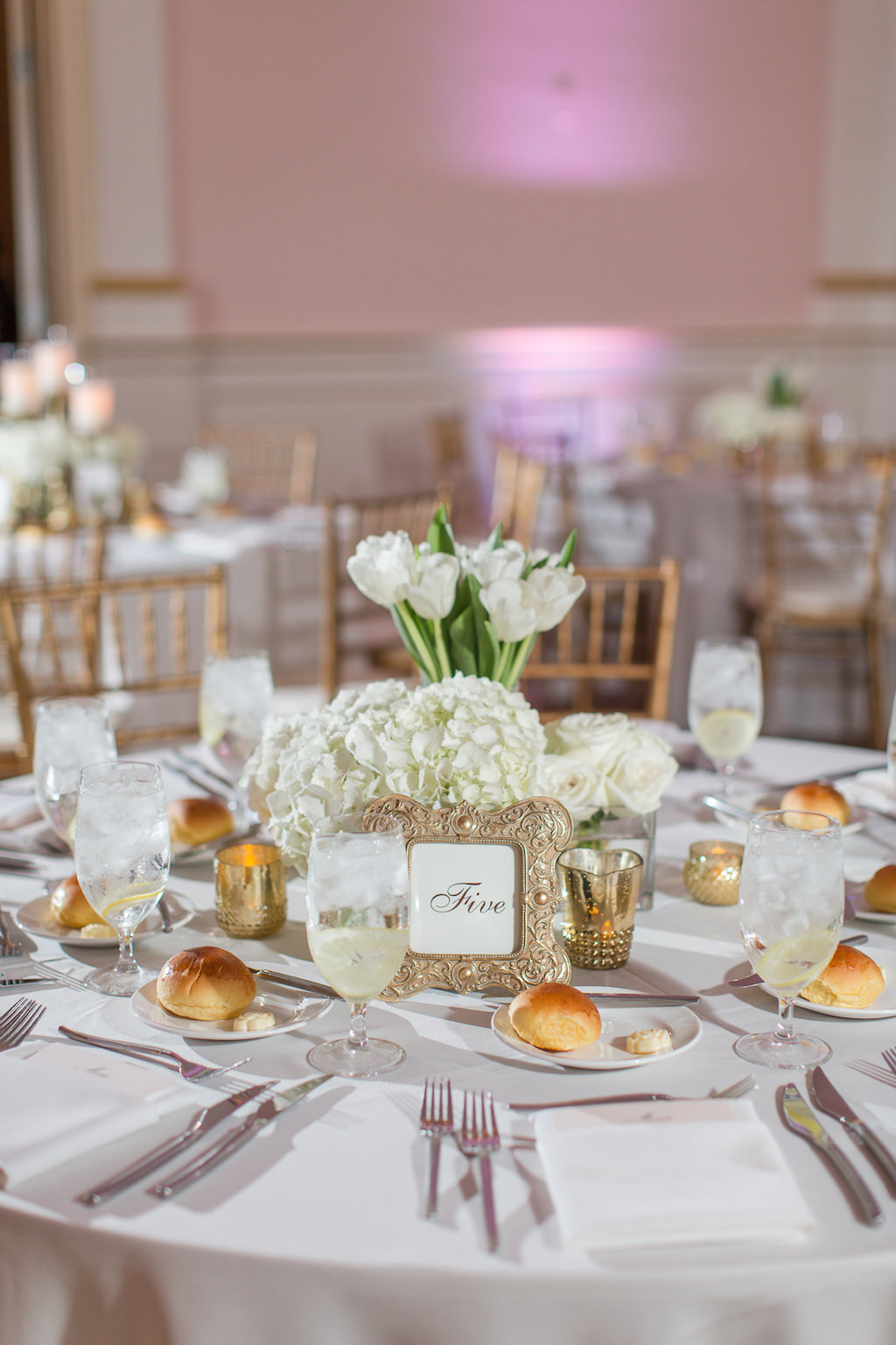 Romantic Classic Elegant Wedding Reception Decor, Round Tables with White Linens, Low White Hydrangeas and White Tulip Floral Centerpieces, Gold Frame with Table Number | Wedding Rentals and Catering by Olympia Catering