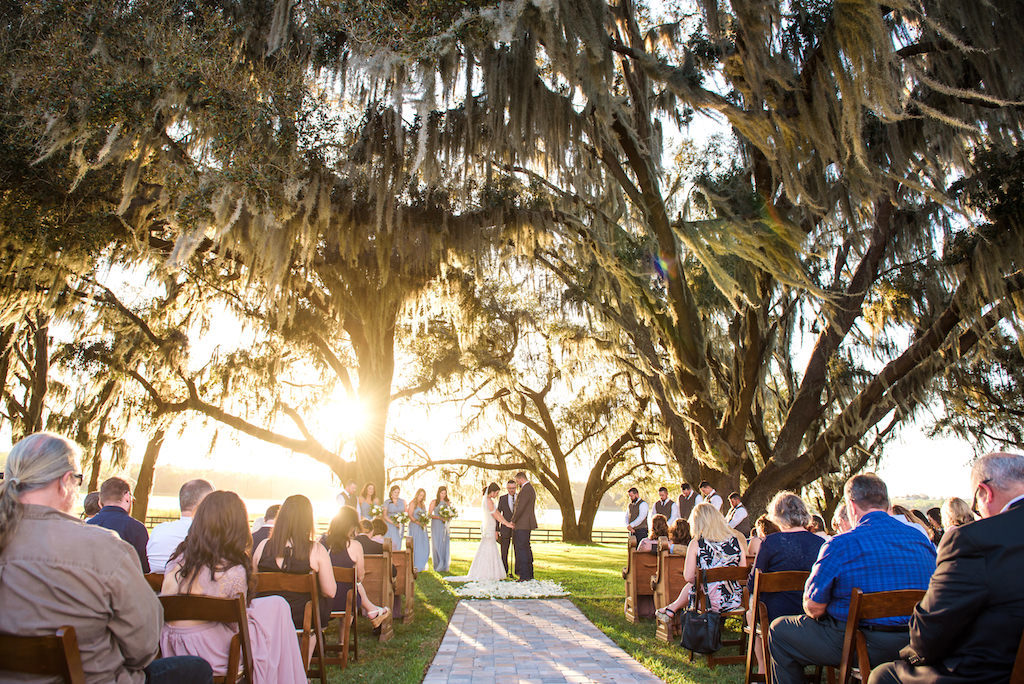 Florida Bride and Groom Exchanging Vows During Wedding Ceremony Under Spanish Moss Trees Sunset Photo | Tampa Bay Rustic Wedding Venue Covington Farms