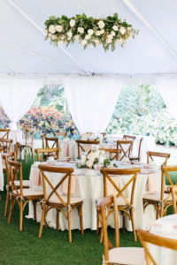 Elegant, Simple, Classic Garden Outdoor Tent Wedding Reception Decor, Hanging Greenery and White Ivory Floral Wreath, String Lights, Round Tables with White Linens, Wooden Crossback Chairs, Hurricane Glass Candlestick Centerpieces | Tampa Bay Wedding Rentals Gabro Event Services
