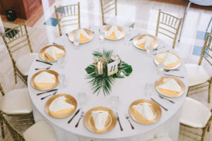 Modern Classic Tropical Wedding Reception Decor, Round Tables with White Linens, Gold Chiavari Chairs, Gold Chargers, Monstera Palm Tree Leaf Centerpiece and Geometric Candle Holders | Wedding Photographer Kera Photography | St. Pete Wedding Venue The Poynter Institute