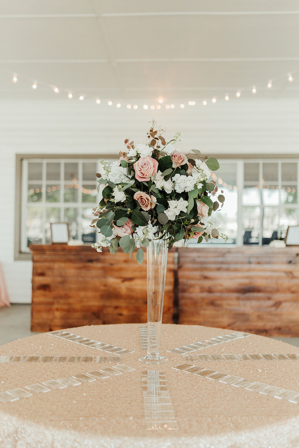 Garden Chic Inspired Wedding Reception Decor, Tall Glass Vase with Mauve, White Florals and Greenery Arrangement on Round Table with Gold Glitter Sparkle Linen