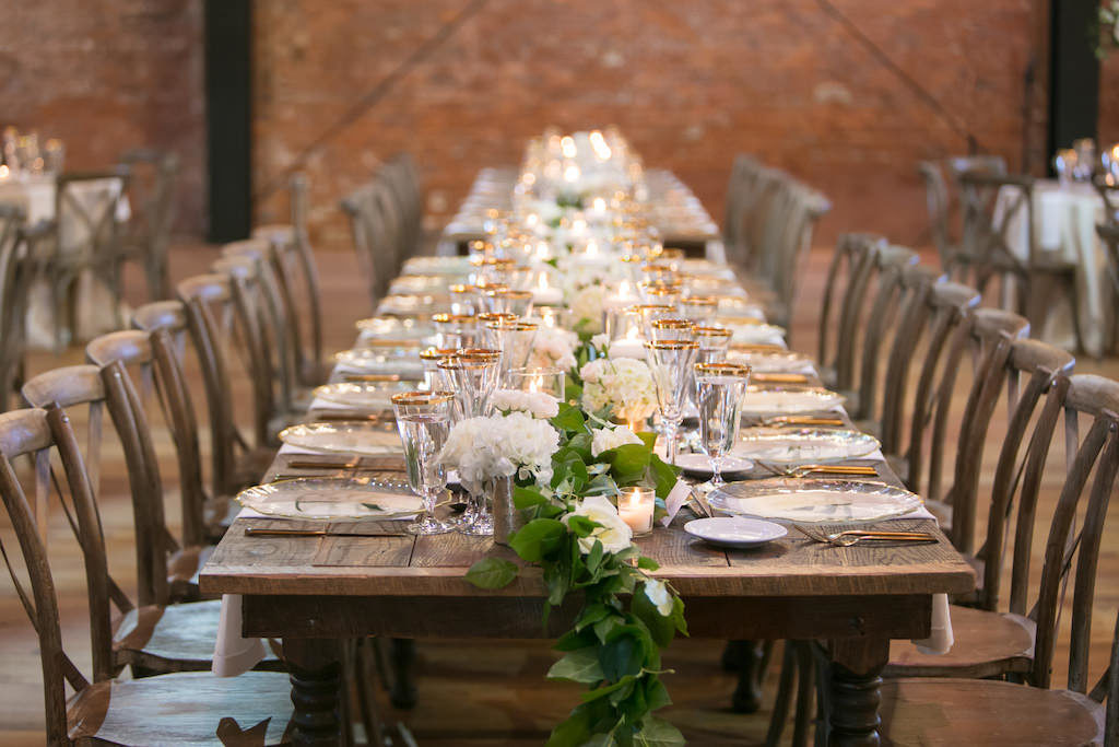 Rustic Modern Elegant Wedding Reception Decor, Long Wooden Feasting Table with Greenery Garland, Wooden Crossback Chairs and White Floral Arrangements | Tampa Bay Wedding Photographer Carrie Wildes Photography | Industrial Tampa Wedding Venue Armature Works | Tampa Wedding and Event Rentals by Kate Ryan Event Rentals