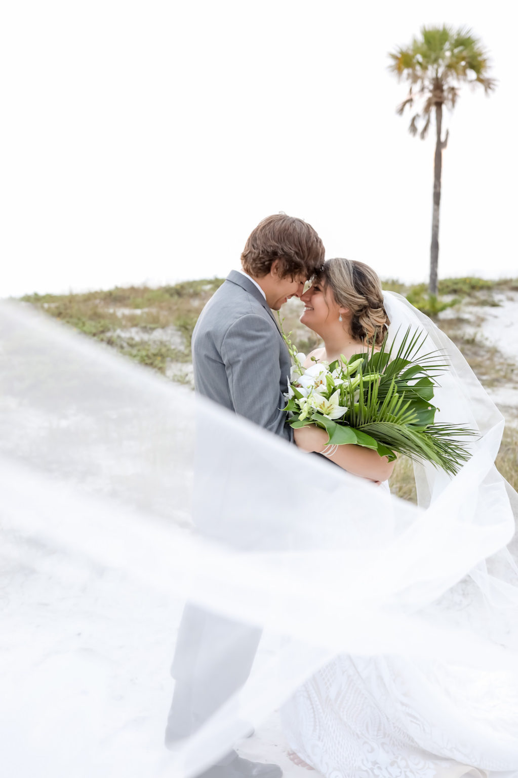 Clearwater Beach Bride and Groom Creative Photo with Cathedral Length Veil Blowing in Wind | Tampa Bay Wedding Photographer Lifelong Photography Studios