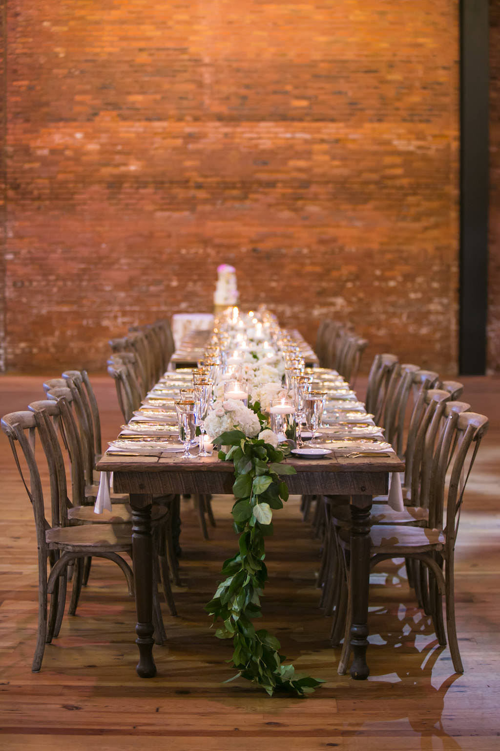 Rustic Modern Elegant Tuscan Inspired Wedding Reception Decor, Long Wooden Feasting Table with Greenery Garland, Wooden Crossback Chairs | Tampa Bay Wedding Photographer Carrie Wildes Photography | Tampa Wedding and Event Rentals by Kate Ryan Event Rentals | Industrial Tampa Wedding Venue Armature Works