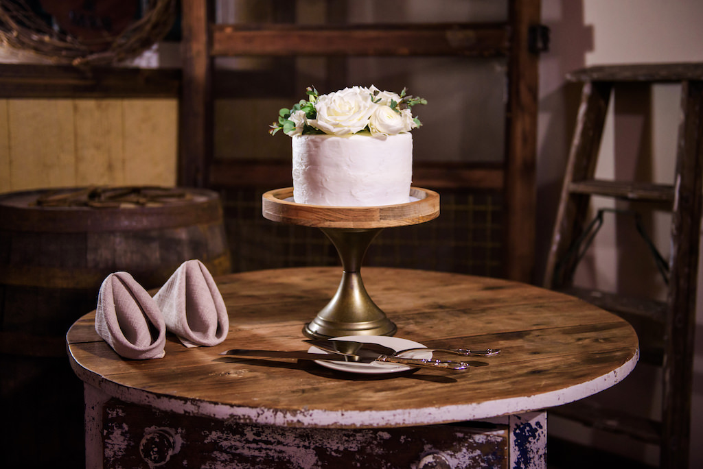 Classic White One Tier Wedding Cake with Real Ivory Roses Cake Topper on Rustic Wooden Cake Stand | Tampa Wedding Rental Linens and Napkins by Over the Top Rental Linens