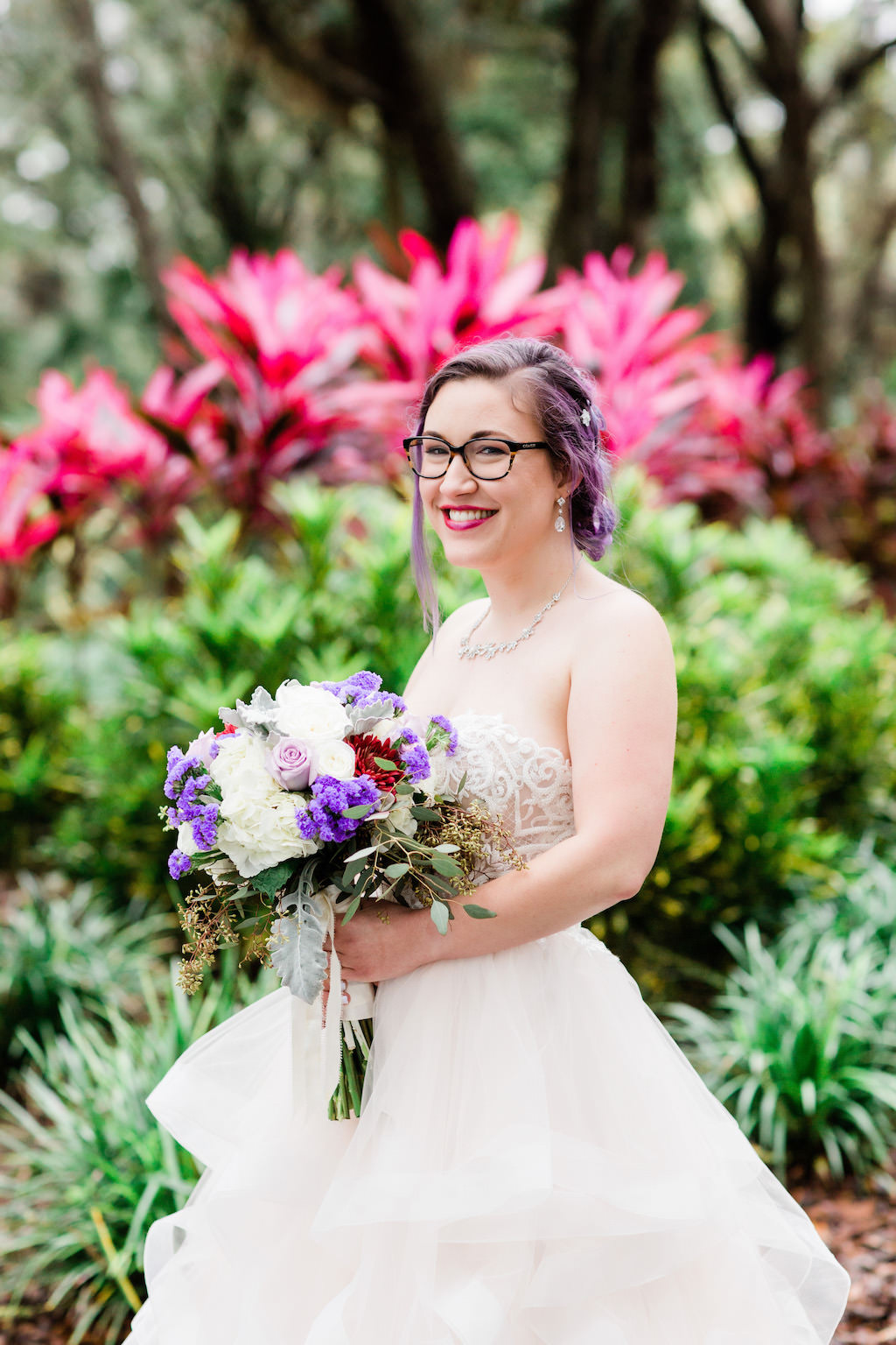 Modern, Romantic Florida Bride in Ballgown Wedding Dress, Unique Wedding Style with Purple Hair and Glasses, Holding Whimsical Bridal Bouquet, Purple, Ivory, White, Red, Flowers with Greenery