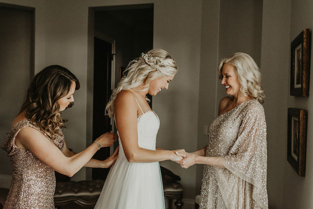 Florida Bride Getting Ready Wedding Portrait with Mom and Bridesmaids in Gold Sequin Dress and Bride in Spaghetti Strap Sweetheart Neckline Lace Bodice and Tulle Skirt Wedding Dress, Curled Half Updo with White Baby Breaths Floral Accessory | Tampa Bay Wedding Hair and Makeup Femme Akoi