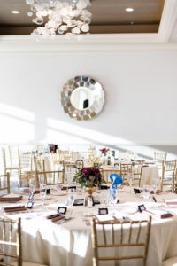 Classic Elegant Wedding Reception Decor, Round Tables with Champagne Linen, Gold Chiavari Chairs, Low Gold Vase with Red and Greenery Floral Centerpiece | Clearwater Beach Wedding Venue Hyatt Regency Clearwater Beach| Wedding Rentals Over the Top Rental Linens