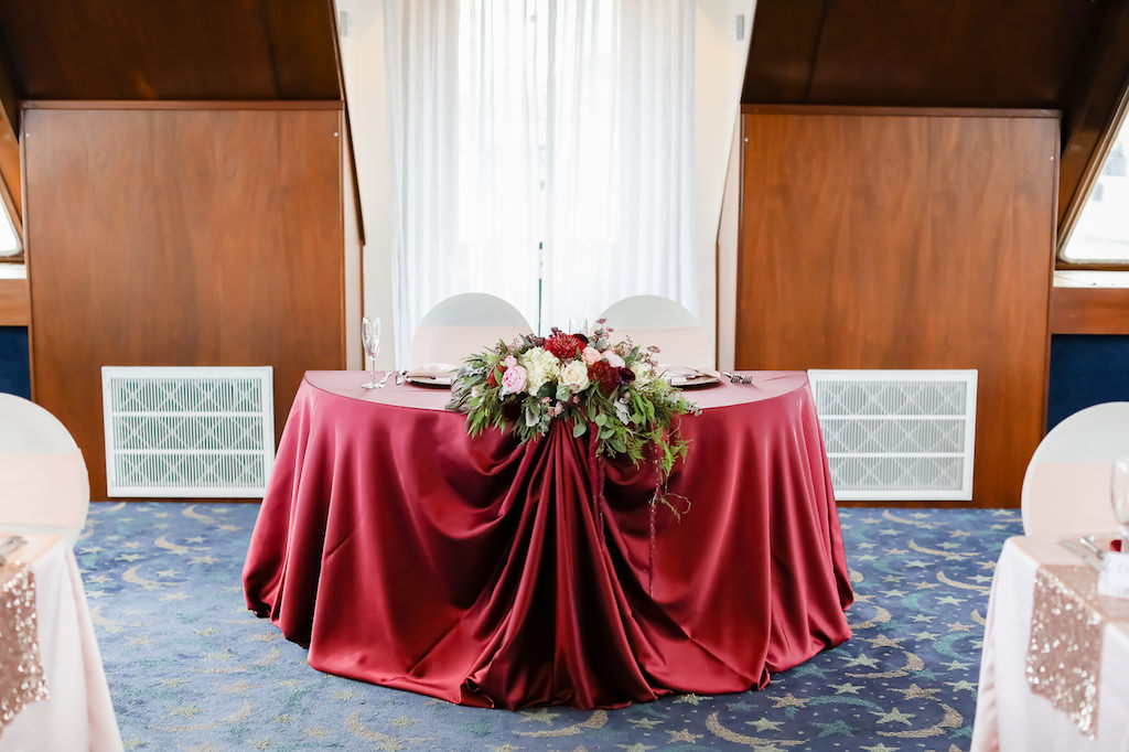 French Country Inspired Wedding Reception Decor, Sweetheart Table with Burgundy Red Silk Linen, Greenery, Red, White, Ivory, Blush Pink Floral Arrangement | Tampa Bay Wedding Photographer Lifelong Photography Studio | Wedding Rentals Kate Ryan Event Rentals | Clearwater Waterfront Wedding Venue Yacht Starship