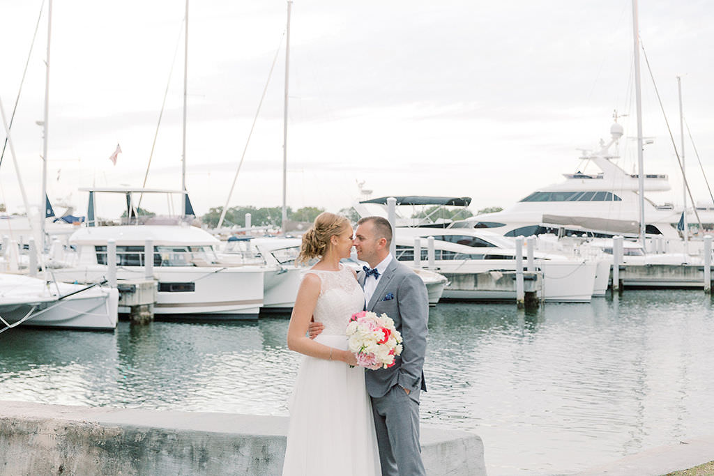 St. Petersburg Bride and Groom Waterfront Yacht Dock Portrait, Bride in High Crewneck Illusion and Lace Wedding Dress and Braided Updo Holding Pink, Blush Pink, Ivory Floral Bouquet