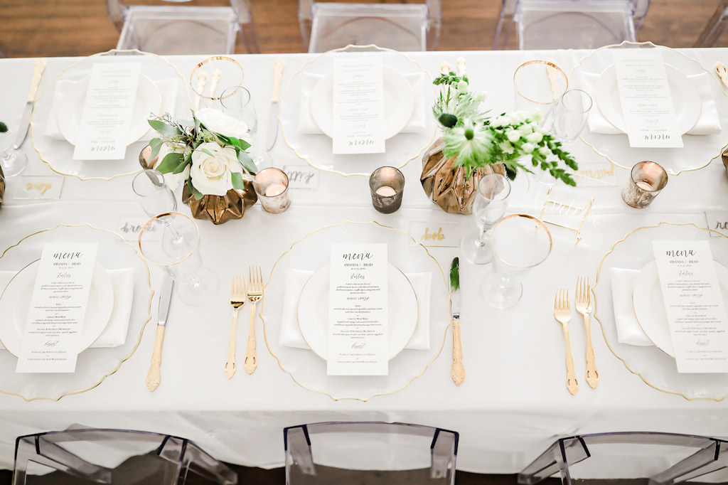 Classic Neutral Wedding Reception Decor, Long Feasting Table with White Linen, Clear Glass and Gold Rimmed Charger, Gold Silverware, Low Gold Vase with Greenery and Ivory Floral Centerpieces, Gold Mercury Candles | Tampa Bay Wedding Photographer Lifelong Photography Studio | Wedding Rentals Kate Ryan Event Rentals