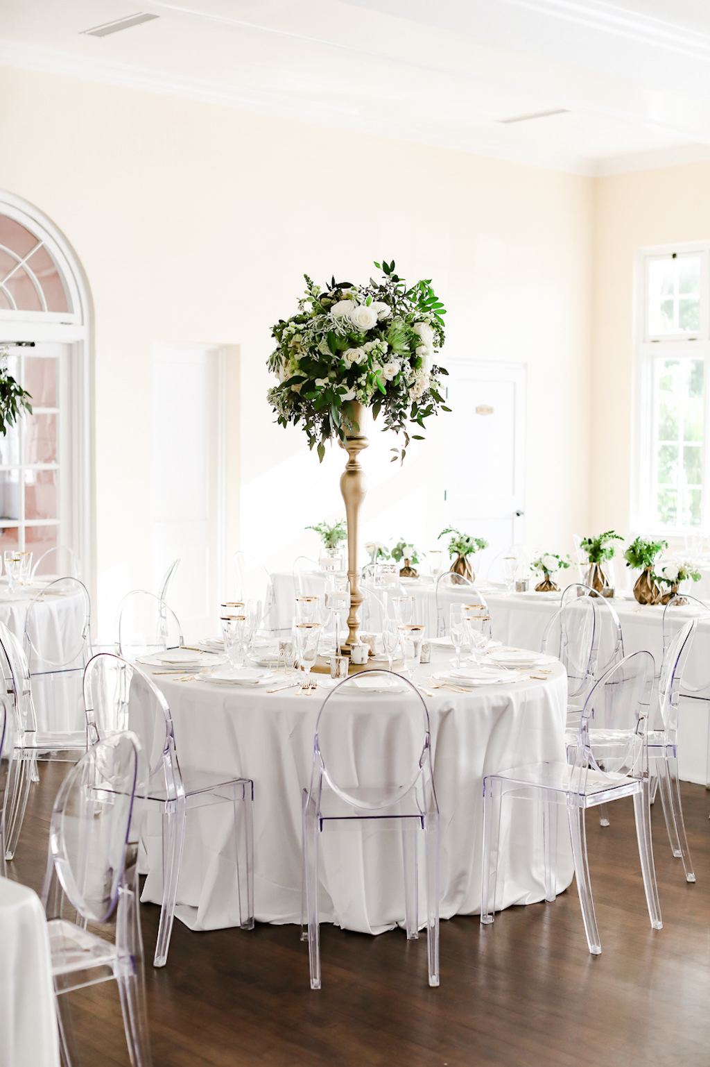 Classic, Neutral Wedding Reception Decor, Round Table with White Linen, Clear Ghost Acrylic Chairs, Tall Gold Candlestick Vase with Greenery and Ivory, White Floral Centerpiece | Tampa Bay Wedding Photographer Lifelong Photography Studio | Wedding Rentals Kate Ryan Event Rentals