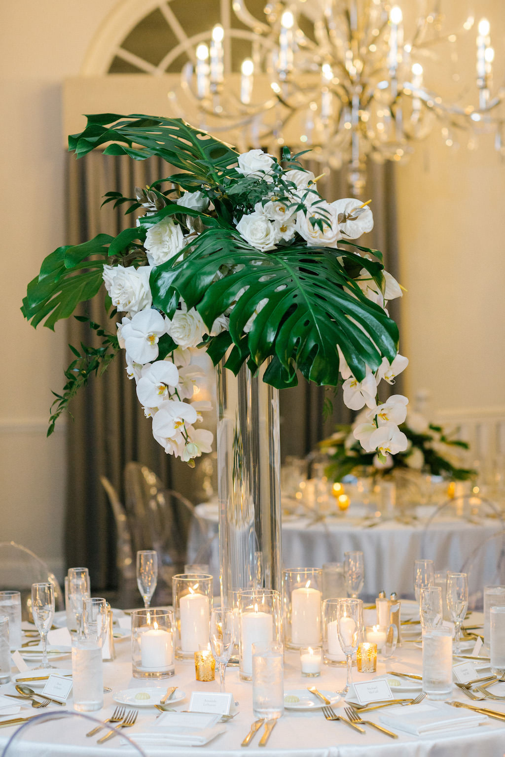 Tropical Modern Elegant Wedding Reception Decor, Tall Glass Cylinder Vase with Monstera Palm Leaf and White Orchids Floral Centerpiece | Tampa Bay Wedding Planner Parties A'La Carte | Wedding Florist Bruce Wayne Florals | Wedding Flatware Rentals from A Chair Affair