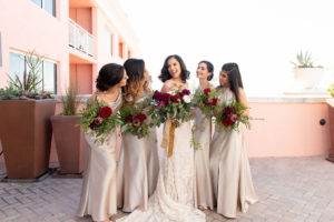 Clearwater Beach Bride Holding Organic Red, Maroon, Greenery and Blush Pink Floral Bouquet with Bridesmaids in Champagne Mix and Match Floor Length Dresses Hotel Rooftop Wedding Portrait | Tampa Bay Wedding Dress Shop Isabel O'Neil Bridal | Wedding Attire Bella Bridesmaids | Waterfront Clearwater Beach Wedding Venue Hyatt Clearwater Beach