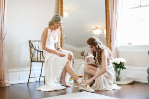 Florida Bride and Bridesmaid Getting Ready Wedding Portrait Putting on White Ballet Flat Wedding Shoes | Tampa Bay Wedding Photographer Lifelong Photography Studio