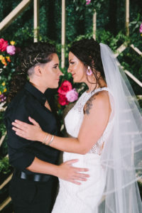 Modern Romantic Lesbian Gay Couple Wedding Portrait, Bride in All Black Suit Shirt and Pants, Bride in White Fitted High Halter Neckline Wedding Dress and Veil | Tampa Bay Wedding Photographer Kera Photography | Sarasota Wedding Dress Shop Truly Forever Bridal | St. Pete Wedding Hair and Makeup Femme Akoi