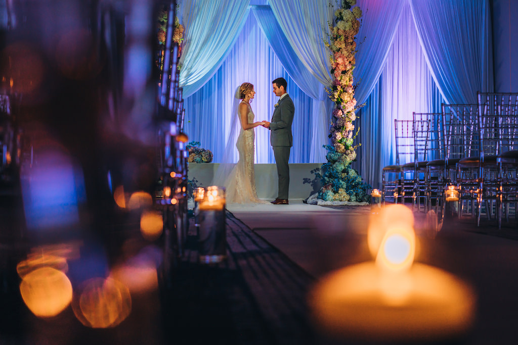 Florida Bride and Groom Wedding Ceremony Portrait, Blue Uplighting, White Draping Ceremony Backdrop, Tall Large Colorful Hydrangeas Floral Pillars, Ghost Acrylic Clear Chiavari Chairs Decor | Tampa Bay Boutique Hotel Wedding Venue Hotel Alba | Wedding Planner Special Moments Event Planning | Wedding Rentals and Chair Decor Gabro Event Services | Styled Shoot