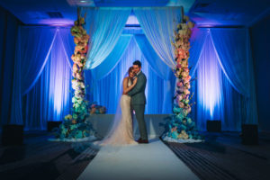 Florida Bride and Groom Intimate Wedding Portrait, Unique Modern Contemporary Wedding Ceremony Decor, Blue Uplighting, Hanging Drapery Backdrop, Tall Large Colorful Floral Pillars by Gabro Event Services | Tampa Bay Boutique Hotel Wedding Venue Hotel Alba | Wedding Planner Special Moments Event Planning | Styled Shoot