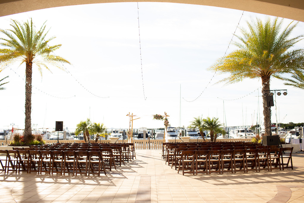Elegant Classic Outdoor Waterfront Yacht Terrace Wedding Ceremony Portrait, Brown Wooden Folding Chairs and Hanging String Lights | Tampa Waterfront Wedding Venue Westshore Yacht Club