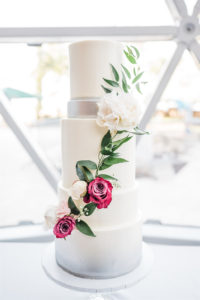 Modern White with Silver Accent Four Tier Wedding Cake with Cascading Magenta Pink and White with Greenery Flowers | St. Pete Wedding Cake Bakery The Artistic Whisk | Tampa Wedding Planner and Florist John Campbell Weddings