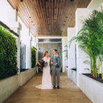 Florida Bride and Groom Wedding Portrait in Boutique Tampa Hotel Alba Hallway, Bride in Lace and Illusion Deep V Neckline Fitted Silhouette Wedding Dress, Groom in Grey Suit with Blue Tie | Wedding Attire Truly Forever Bridal | Styled Shoot