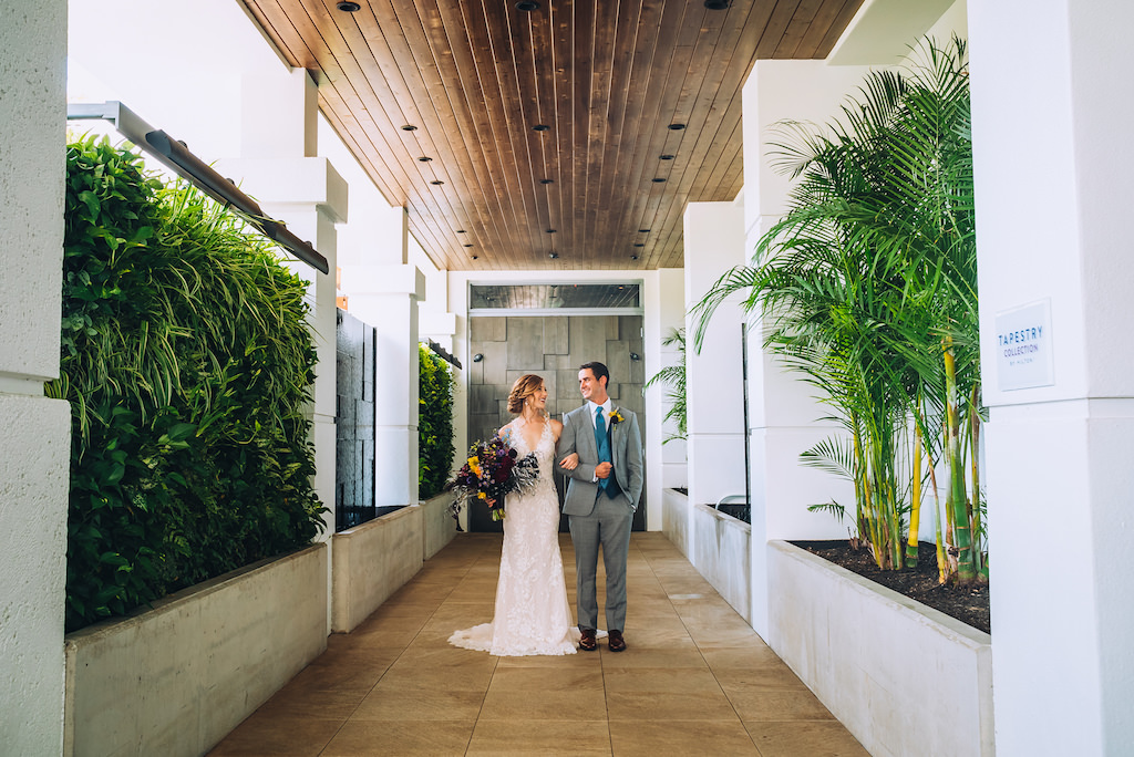 Florida Bride and Groom Wedding Portrait in Boutique Tampa Hotel Alba Hallway, Bride in Lace and Illusion Deep V Neckline Fitted Silhouette Wedding Dress, Groom in Grey Suit with Blue Tie | Wedding Attire Truly Forever Bridal | Styled Shoot