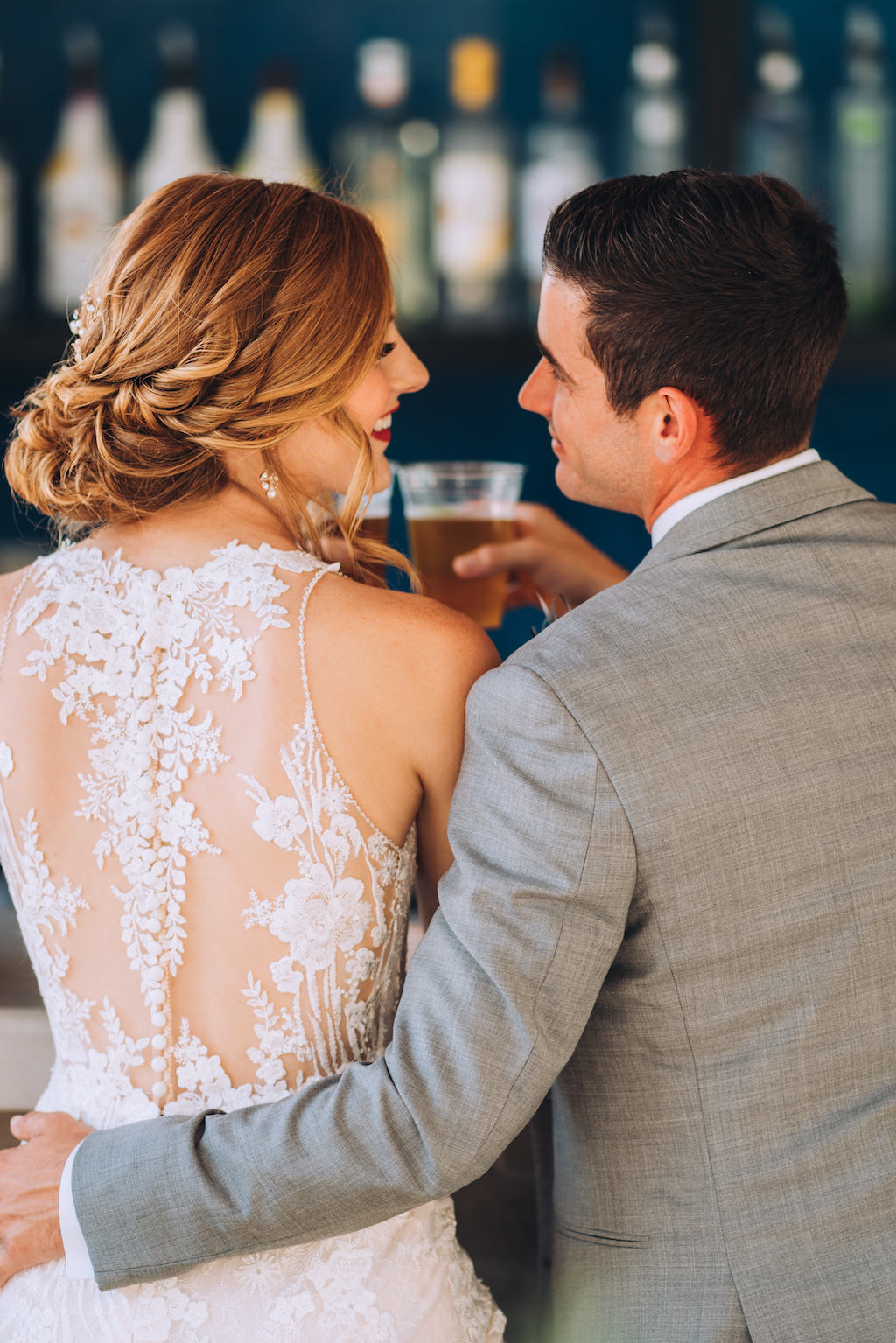 Fun Tampa Bay Bride and Groom Cheering Wedding Portrait, Bride with Loose Romantic Updo, Lace and Illusion High Back with Buttons Wedding Dress, Groom in Gray Suit | Wedding Attire Truly Forever Bridal | Wedding Hair and Makeup Michele Renee the Studio | Styled Shoot