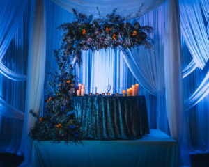Contemporary Modern Wedding Reception Decor, Linen Drapery, Blue Uplighting, Sweetheart Table, Elegant Blue Linen, Candles, Unique Moody Dramatic Orange and Blue Floral Arrangements | Tampa Bay Wedding Planner Special Moments Event Planning | Wedding Rentals Gabro Event Services | Styled Shoot