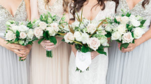 Florida Bride and Bridesmaids in Mix and Match Silver, Gray and Nude Dresses Holding Garden Inspired Blush Pink and Ivory Roses with Yellow and Green Leaves and Dusty Miller Floral Bouquets