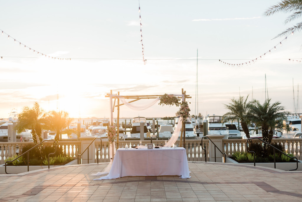 Elegant Wedding Decor Sunset Portrait, Bamboo Arch with Floral Arrangements and White Linen Draping | Tampa Waterfront Wedding Venue Westshore Yacht Club