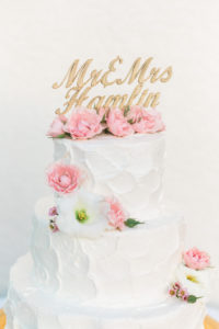 White Wedding Cake with Blush Pink Flowers and Custom Gold Cake Topper