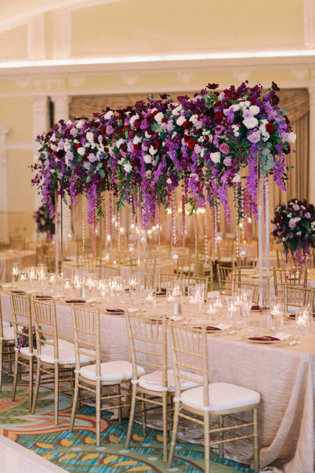Elegant, Extravagant Wedding Reception Decor Portrait, Long Table with Gold Linen, Gold Chiavari Chairs, Tall Purple, Plum, Lilac, Red Greenery and Purple Hanging Amaranthus Floral Centerpiece | Downtown St. Pete Hotel Ballroom Wedding Venue The Vinoy Renaissance